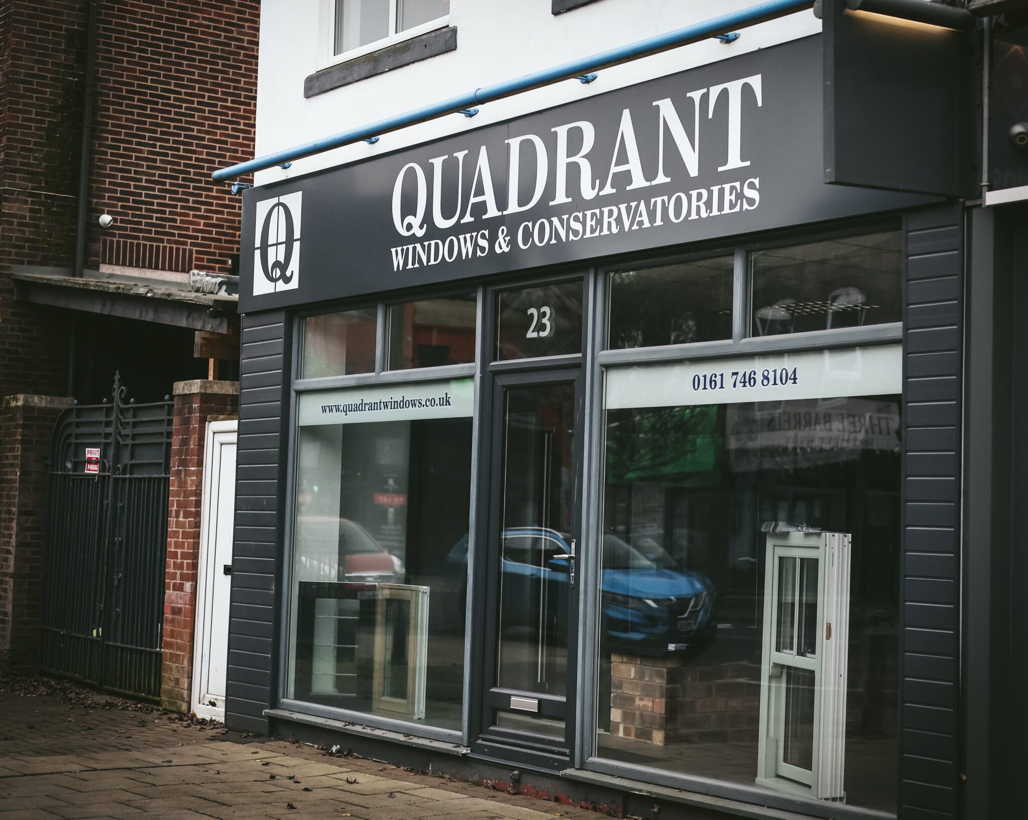 The shopfront of Quadrant Windows & Conservatories features two elegant window displays. Prominently, the signage showcases their website and phone number, highlighting the importance of incorporating SEO keywords for maximum visibility.