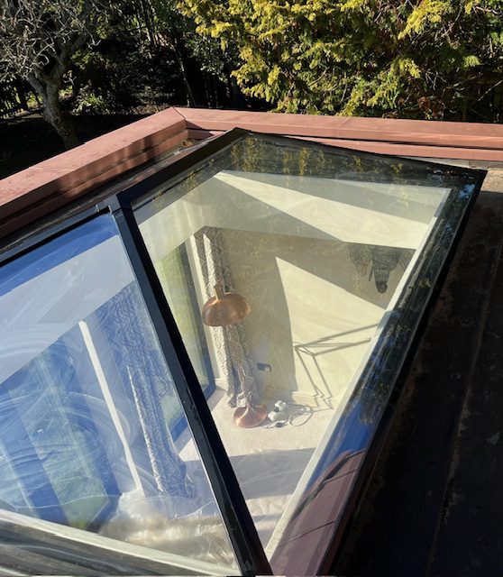 A skylight on a roof, featuring a clear window that allows natural light to illuminate the interior space.