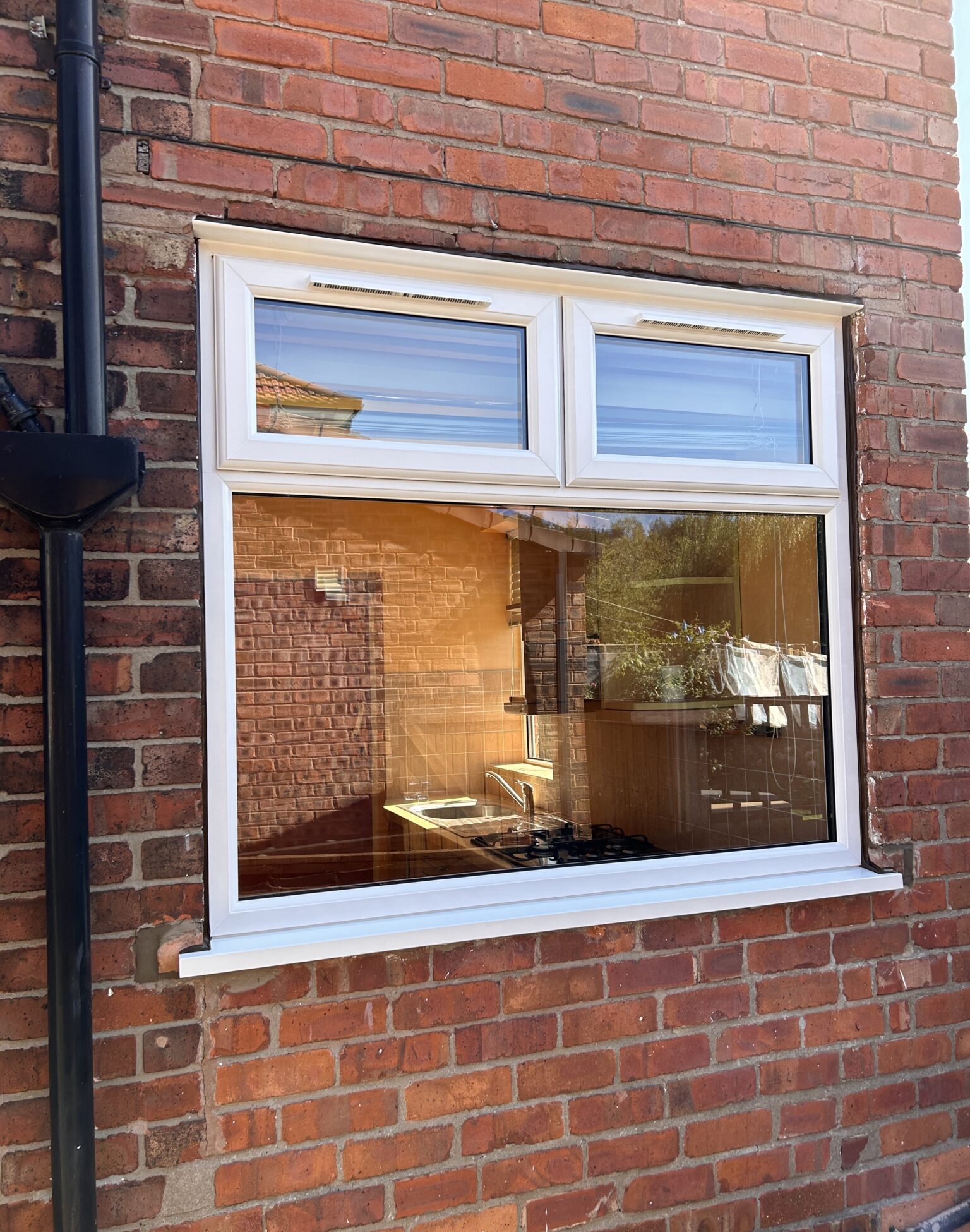 A white-framed window set against a textured brick wall, showcasing a blend of modern and rustic elements.