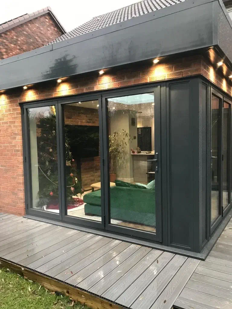 Modern extension with large bi-fold doors and a brick exterior, leading to a decked patio area. Christmas tree visible inside.