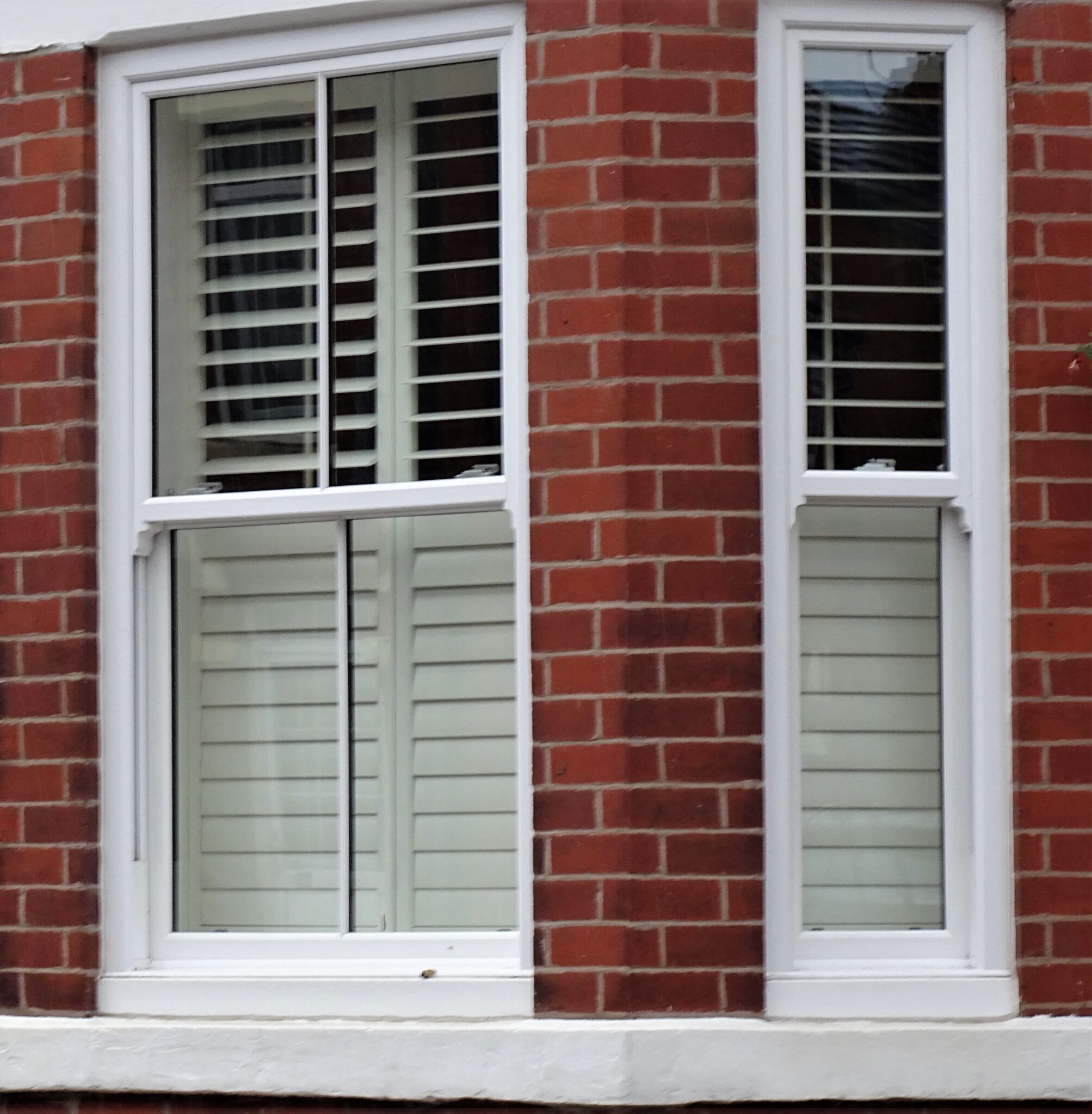 A window with wooden shutters set against a textured brick wall, showcasing a blend of rustic and architectural elements.